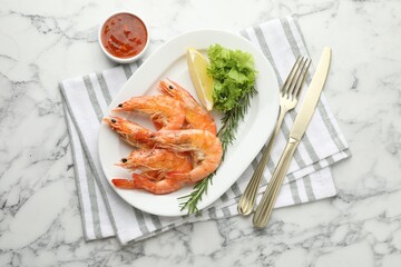Tasty grilled shrimps served with lemon, lettuce, rosemary and sauce on white marble table, flat lay. Delicious seafood dish