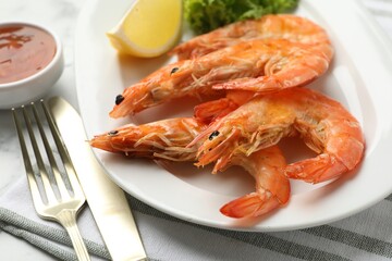 Tasty grilled shrimps served with lemon, lettuce and sauce on table, closeup. Delicious seafood dish