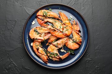 Tasty grilled shrimps with sauce on black table, top view. Delicious seafood dish