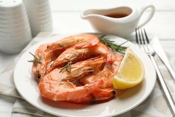 Tasty grilled shrimps served with rosemary, sauce and lemon on white wooden table, closeup. Delicious seafood dish