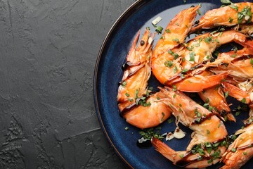 Delicious seafood dish. Tasty grilled shrimps with sauce on black table, top view. Space for text