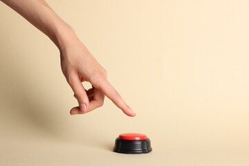 Woman pressing red button on beige background, closeup