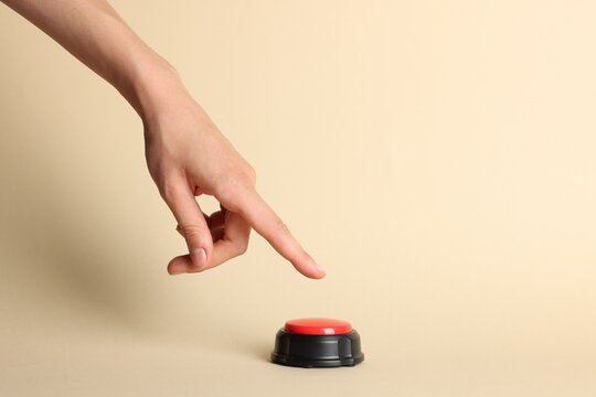 Woman pressing red button on beige background, closeup