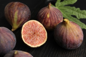 Whole and cut figs on black table, closeup