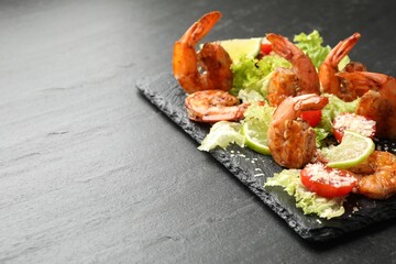 Tasty grilled shrimps with salad on black table, closeup with space for text. Delicious seafood dish