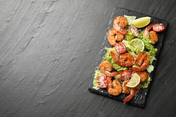 Tasty grilled shrimps with salad on black table, top view with space for text. Delicious seafood dish