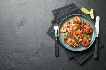 Tasty grilled shrimps with herbs and spices served on black table, flat lay with space for text. Delicious seafood dish
