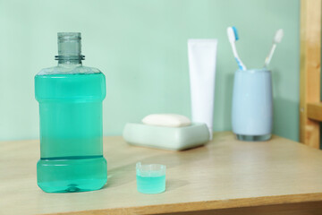 Bottle and cap of mouthwash on wooden shelf in bathroom