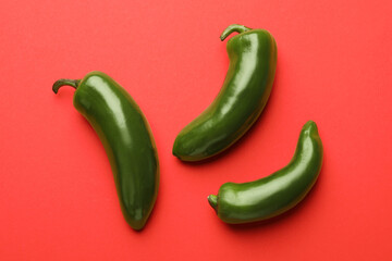 Green jalapeno peppers on red background, flat lay