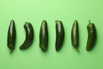Ripe jalapeno peppers on light green background, flat lay