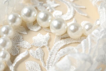 Beautiful pearl necklace on lace fabric, closeup