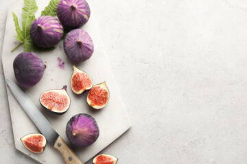 Fresh ripe figs, knife and green leaf on gray textured table, top view. Space for text