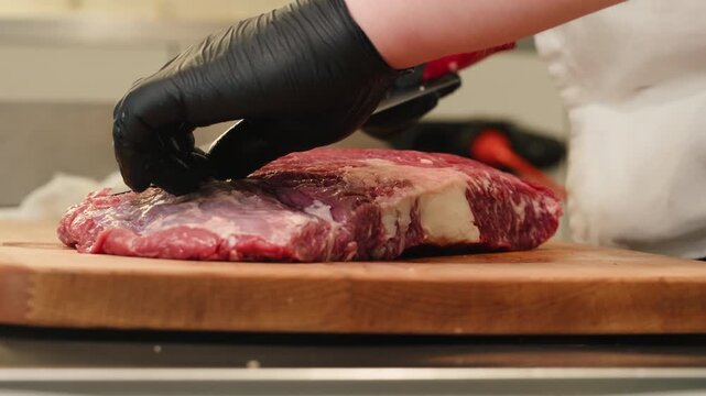 Working with beef, cut steak Chef cooking Raw beef meat tartar with sauce, man cutting steak tartare, making delicious french dish in modern restaurant. Fresh eco angus meat. 