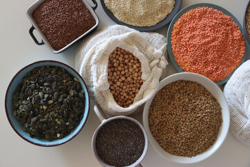 Bowls and bags full of various healthy grains and legumes. Top view.