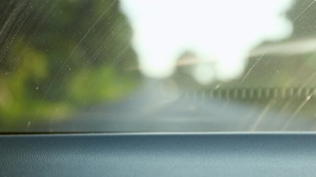 inside view of windshield and moving car, looking through a slightly dusty windshield during a holiday road trip on a sunny morning, capturing the mood of travel and relaxation while driving