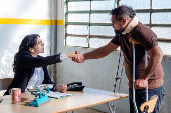 Young female lawyer or social worker shaking hands with injured man victim of accident