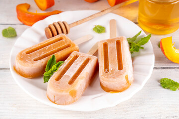 Sweet tasty pumpkin and honey popsicles ice cream. Frozen sorbet gelato on sticks, made with pumpkin squash puree and golden honey, delicious autumn dessert, copy space