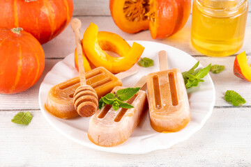 Sweet tasty pumpkin and honey popsicles ice cream. Frozen sorbet gelato on sticks, made with pumpkin squash puree and golden honey, delicious autumn dessert, copy space