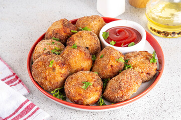 Homemade tasty airfryer made fish patties. Big plate of hot fish cutlets, with crispy crust, fried without oil. Healthy balanced food, high protein source recipe, with ketchup sauce on white table