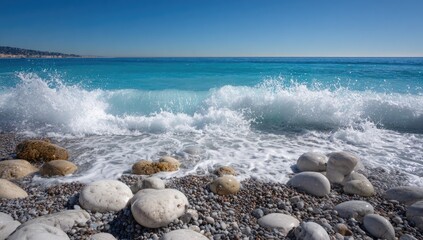 Turquoise ocean waves crashing on a pebble beach with clear blue sky.