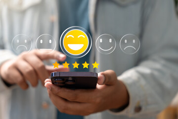 Satisfaction review, User giving five-star rating with happy emoji icon on smartphone screen, representing excellent customer feedback, digital reputation, and mobile user experience concept.