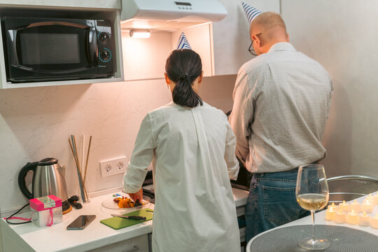 Couple Cooking Birthday Dinner Kitchen: A man and woman prepare a meal in their apartment kitchen for a birthday celebration.