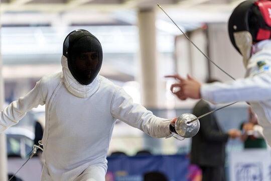Fencers competing in match wearing protective gear with swords - Powered by Adobe