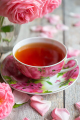A cup of aromatic tea, a book and a rose on the table.