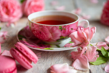 A cup of aromatic tea, a book and a rose on the table.