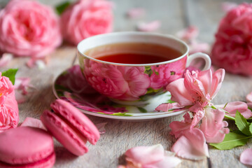 A cup of aromatic tea, a book and a rose on the table.