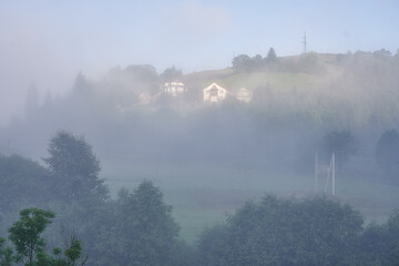 fog in the mountains houses at altitude green forest summer