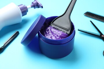 Care cosmetic product for blonde hair in jar and hairdresser's tools on light blue background, closeup