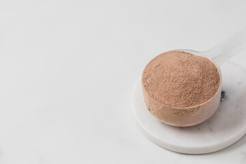 Protein chocolate powder scoop on marble surface. Copy space