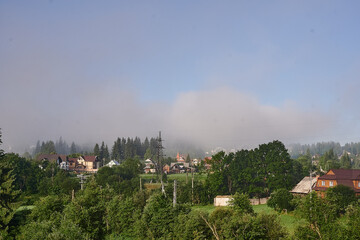 fog in the mountains houses at altitude green forest summer