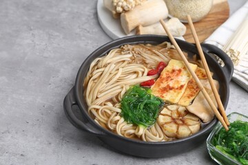 Tasty ramen with enoki and king oyster (eryngii) mushrooms on light grey table, closeup