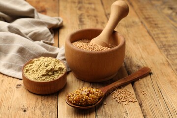 Different types of mustard on wooden table, closeup