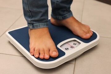 Little boy standing on scales indoors, closeup