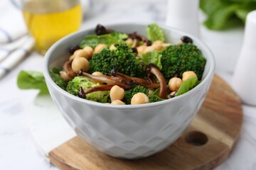 Delicious salad with shimeji mushrooms, chickpeas and broccoli in bowl on table, closeup