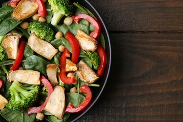Tasty salad with eryngium mushrooms, chickpeas, vegetables and spinach on wooden table, top view. Space for text