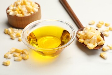 Corn oil and kernels on white table, closeup