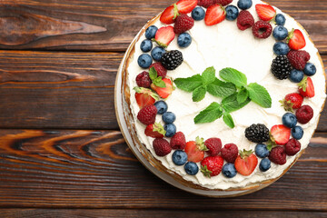 Delicious crepe cake with fresh berries on wooden table, top view. Space for text