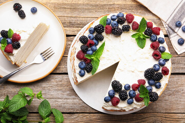 Tasty crepe cake with berries on wooden table, flat lay