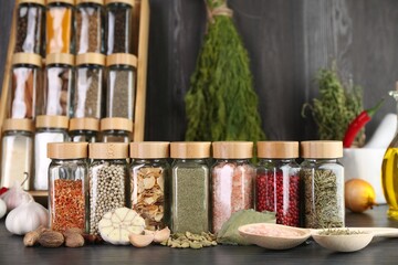 Different spices and glass jars on grey wooden table