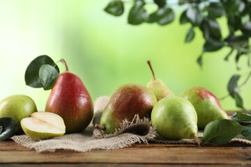 Fresh ripe pears with green leaves on wooden table, closeup