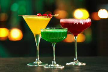 Glasses of alcoholic cocktails on table against blurred background