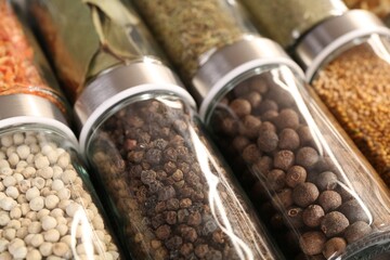 Different spices in glass jars as background, closeup