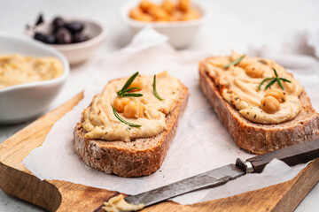 Delicious sandwiches with hummus and ingredients on white table, flat lay. High quality photo