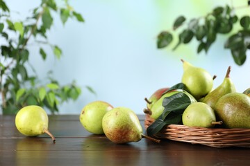 Fresh ripe pears on wooden table and green leaves outdoors, closeup