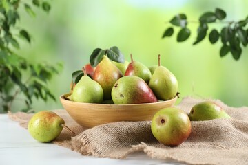 Fresh ripe pears on white marble table and green leaves outdoors, closeup