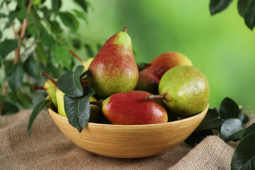 Fresh ripe pears on table and green leaves outdoors, closeup